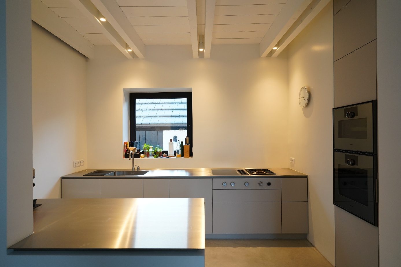 Moderne Küche mit Edelstahl-Arbeitsplatte, grauen Fronten und Gaggenau-Einbaugeräten